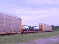 Two GMC trucks go east of Drummondville on a CNA flat car