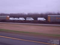 Brand new delivery trucks on a flat car move on a CN train